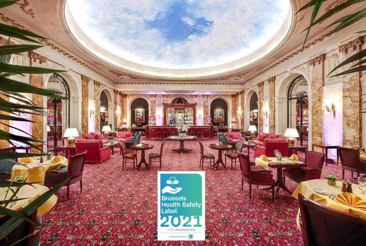 布鲁塞尔广场酒店  外观 照片 The photo shows an elegantly designed interior space, likely a hotel or a high-end restaurant. The room is adorned with opulent decor, featuring rich colors and luxurious furnishings, including pink plush seating and ornate tables. The flooring is ca