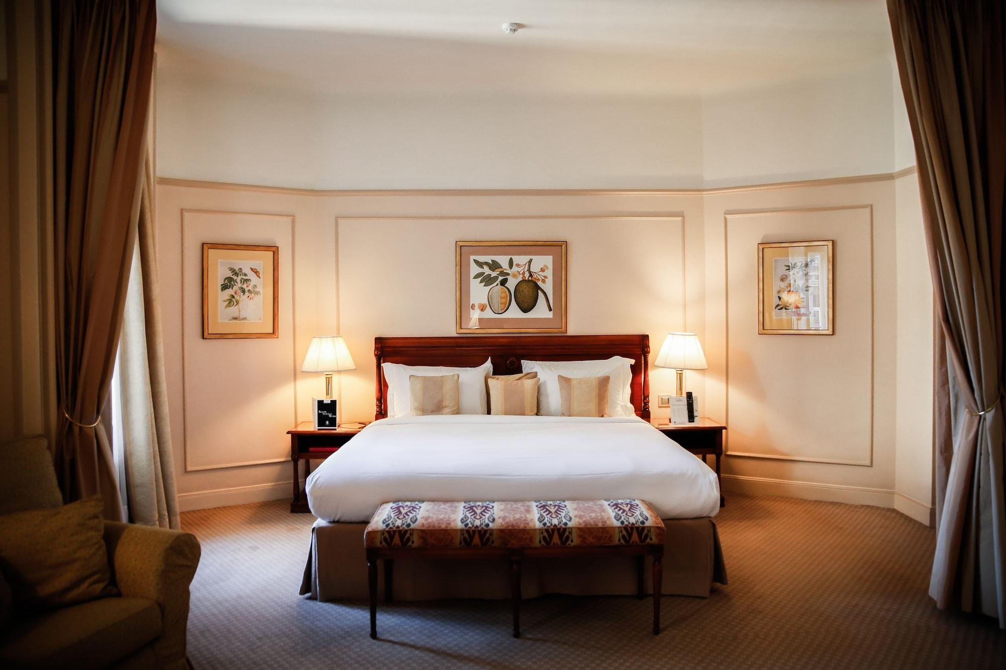 布鲁塞尔广场酒店  外观 照片 The photo shows a well-decorated bedroom. It features a large bed with white linens and several decorative pillows. On either side of the bed, there are bedside tables with lamps. The walls are adorned with framed botanical prints, adding a touch of 