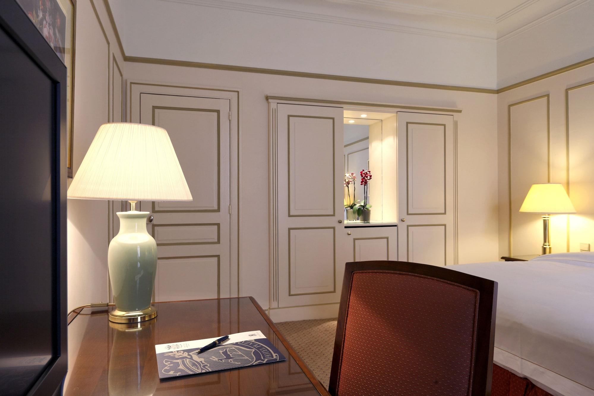 布鲁塞尔广场酒店  外观 照片 The photo shows a well-decorated hotel room or a similar living space. On the left side, there is a desk with a lamp, a piece of paper, and a pen placed on it. The wall behind the desk features elegant paneling, and there is a television visible. On 