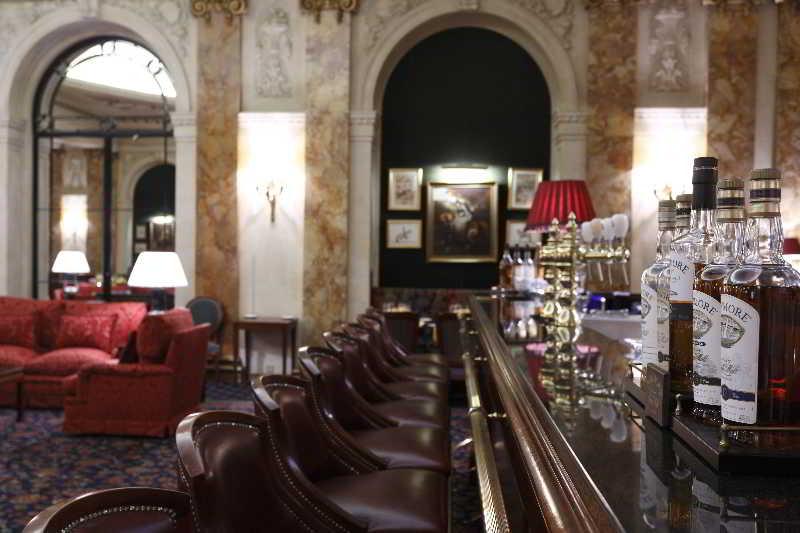 布鲁塞尔广场酒店  外观 照片 The photo depicts an elegant interior of a bar or lounge. In the foreground, there's a polished bar counter lined with several plush, high-backed chairs. Behind the bar, a selection of bottles can be seen, indicating a range of alcoholic beverages. T