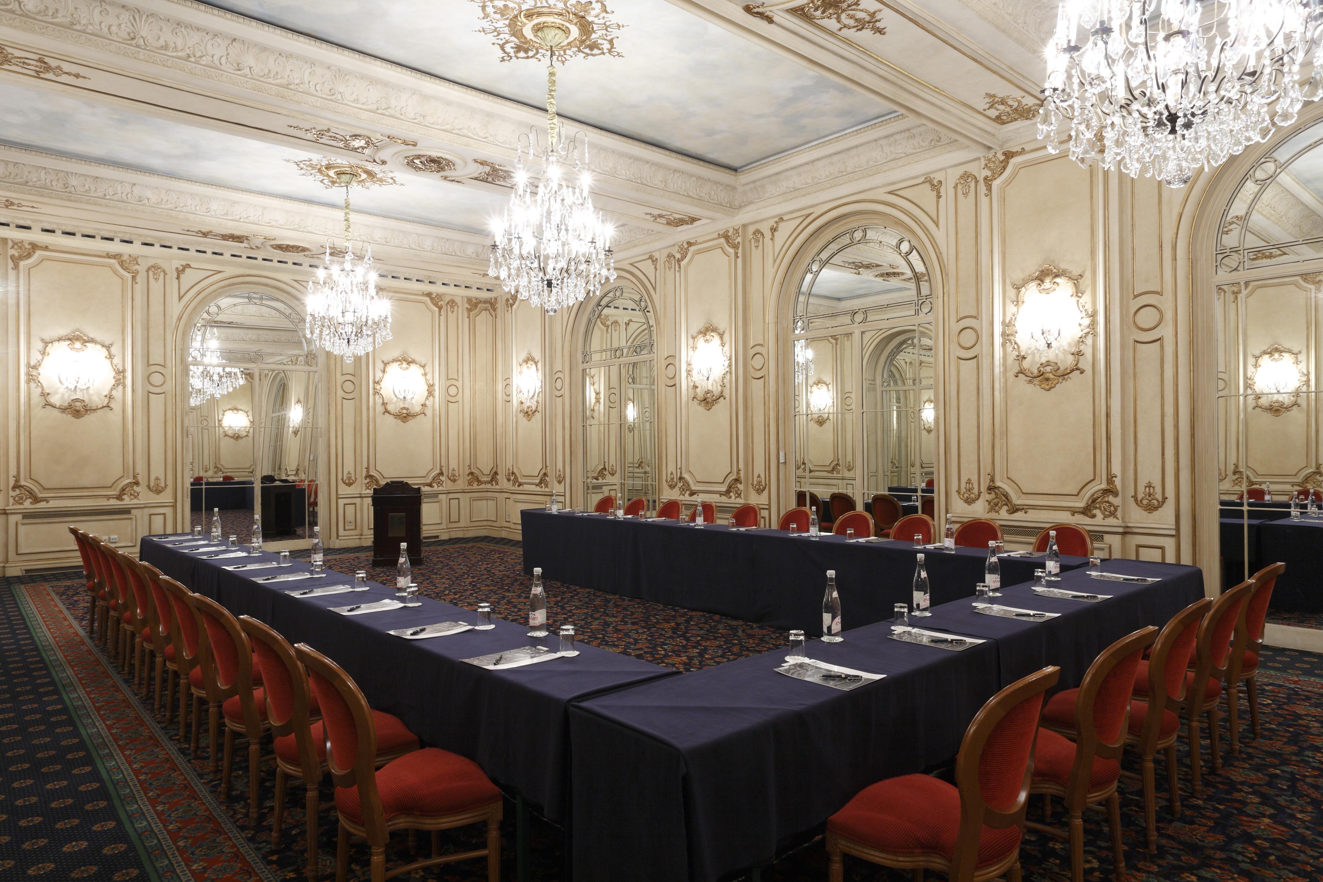 布鲁塞尔广场酒店  设施 照片 The photo shows an elegantly designed conference or meeting room. The room features ornate decorations, with detailed molding and classic architectural elements. There are several chandeliers hanging from the ceiling, providing warm lighting. A large