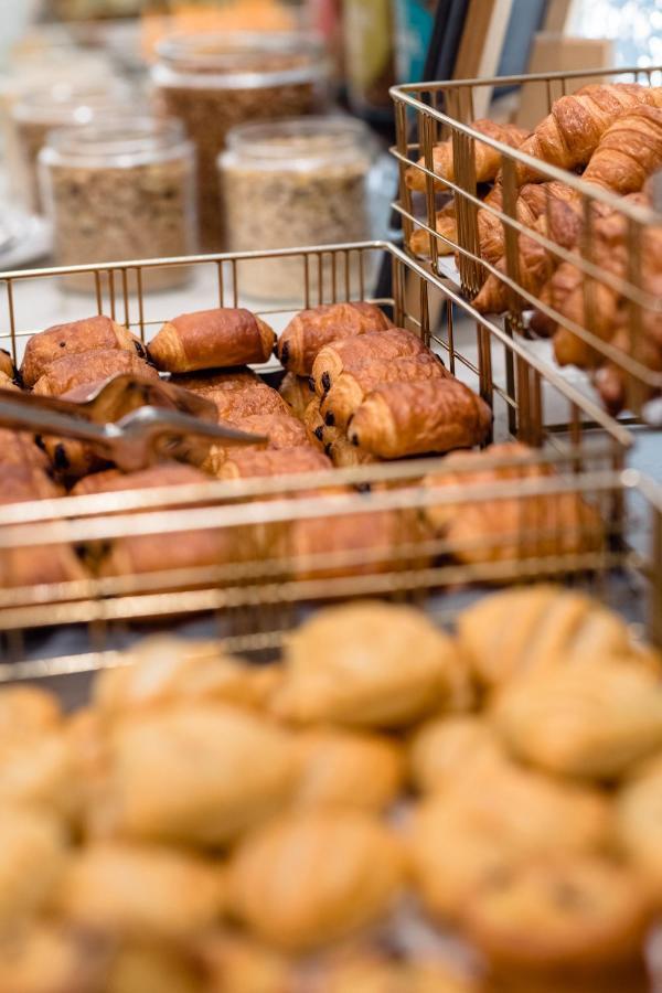 布鲁塞尔广场酒店  外观 照片 The photo shows a selection of baked pastries arranged in metal wire baskets. There are various types of pastries, including croissants and chocolate-filled rolls. Some pastries appear flaky and golden-brown, while others have a slightly darker color