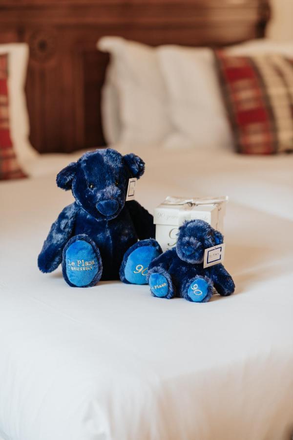 布鲁塞尔广场酒店  外观 照片 The photo features two plush teddy bears. Both bears are a deep blue color and have a shiny, soft texture. The larger bear is sitting upright, while a smaller bear is positioned beside it. Each bear has a tag attached, and the larger bear has "The Pl