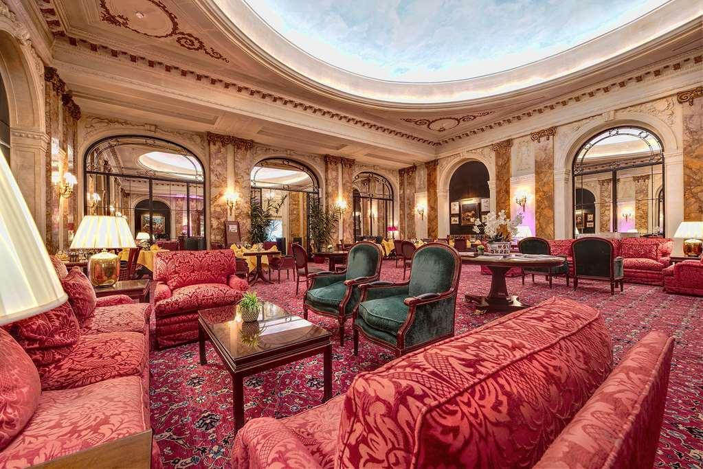布鲁塞尔广场酒店  内观 照片 The photo shows a luxurious and elegant lounge area, characterized by richly decorated furnishings. There are plush red sofas and armchairs arranged in a cozy manner, complemented by a decorative rug on the floor. The space features warm lighting fro