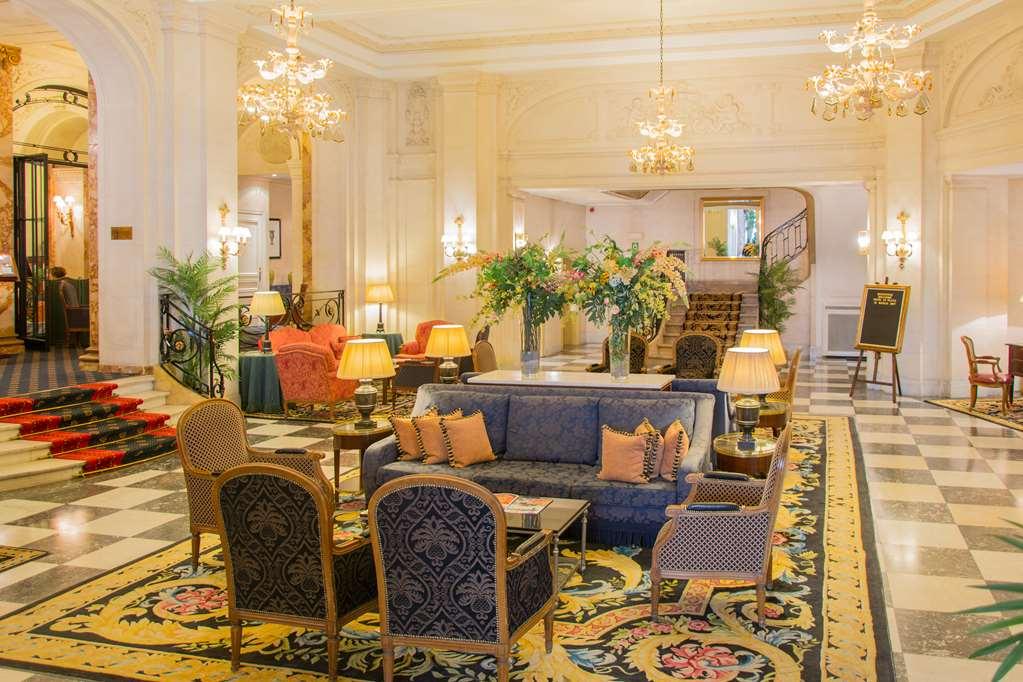 布鲁塞尔广场酒店  内观 照片 The photo depicts a luxurious hotel lobby. It features elegant chandeliers hanging from the ceiling and plush seating arrangements, including a blue sofa and upholstered chairs. A decorative rug lies on the floor, adding to the opulence of the space.