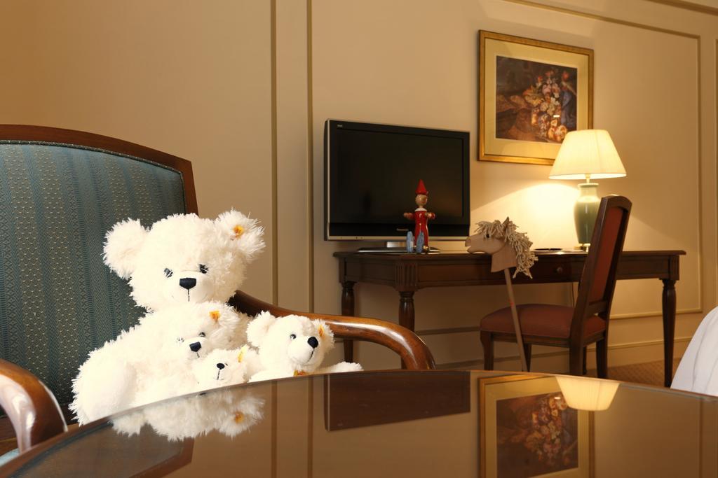 布鲁塞尔广场酒店  外观 照片 The photo depicts a cozy interior setting. In the foreground, there are three white teddy bears sitting on a chair. The bears appear soft and plush, possibly adorned with small decorations like flowers. In the background, there is a wooden desk with 