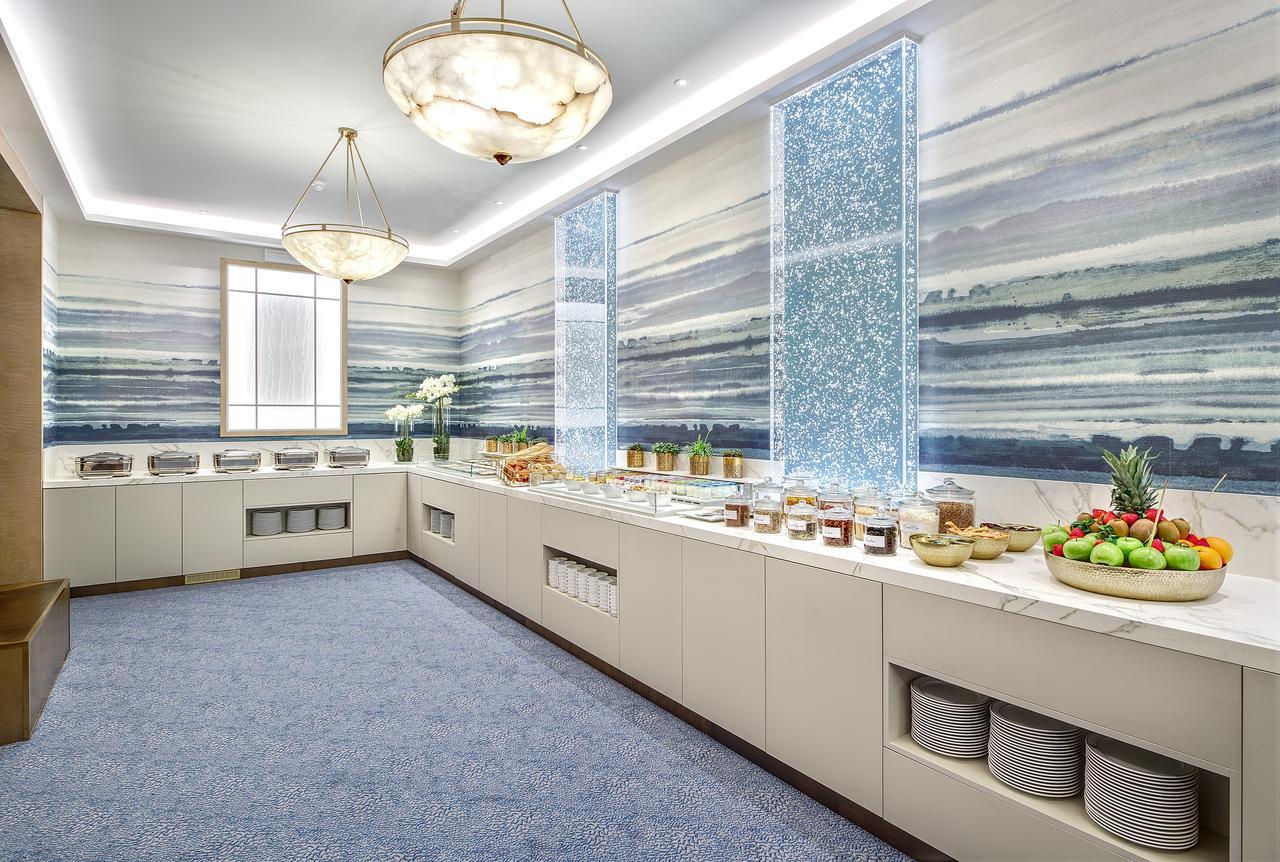 布鲁塞尔广场酒店  外观 照片 The photo depicts a bright and modern dining area or buffet space. The walls are adorned with a large mural featuring flowing, abstract patterns in shades of blue, reminiscent of water or sky. Natural light enters through large windows, which are fra